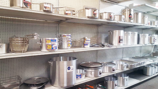 Steel sauce pans of various sizes on shelves inside showroom